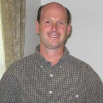 A man in a plaid shirt smiling for the camera.