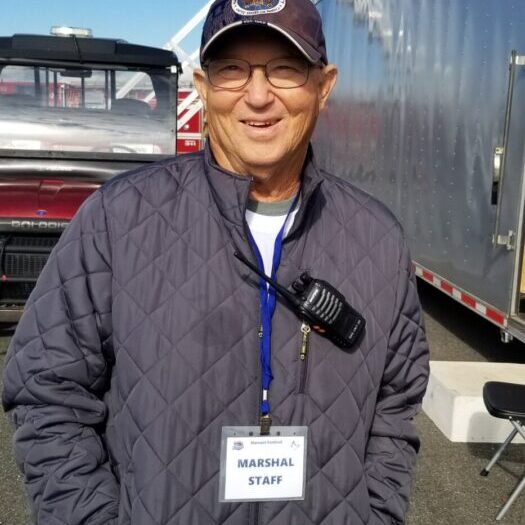 A man in a hat and jacket standing next to a trailer.